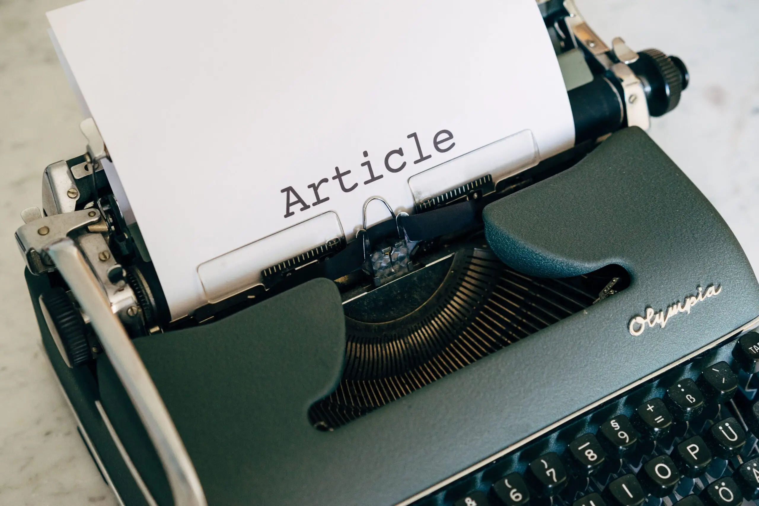 Top view of a vintage Olympia typewriter with paper titled 'Article'.