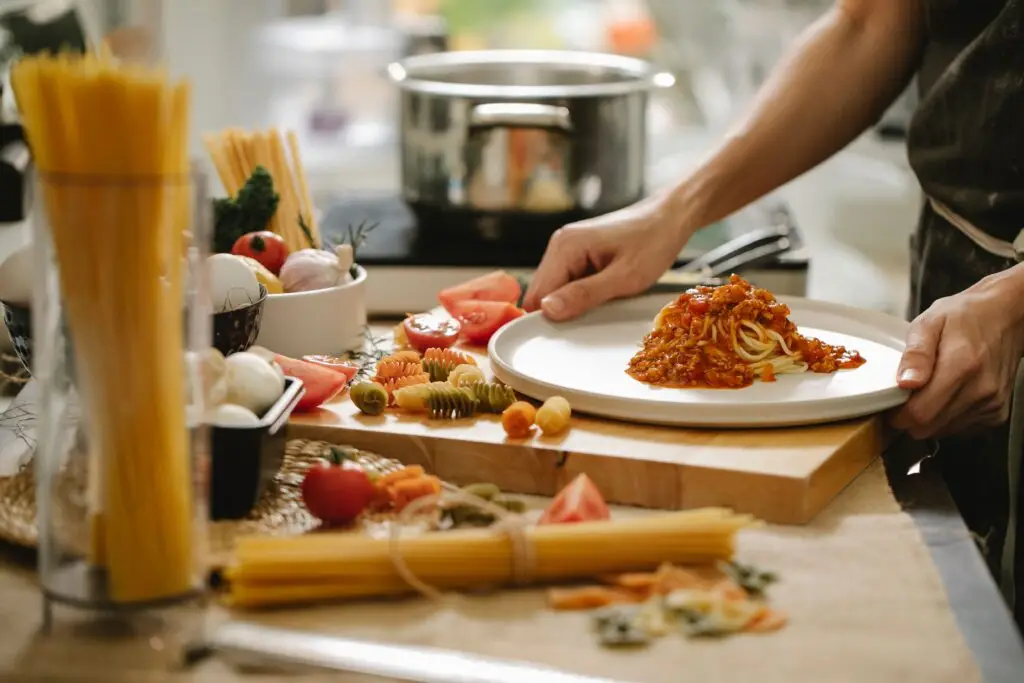 The History of 17th-Century English Cookery: Exploring "The English Housewife" (1683) Crop anonymous cook standing at table with various ingredients and cooking pasta with meat and tomatoes